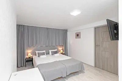 a bedroom with a large white bed and a television at HappyInn Rooms in Kaunas