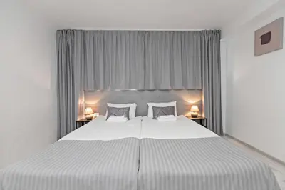 a bedroom with a large white bed with two lamps at HappyInn Rooms in Kaunas