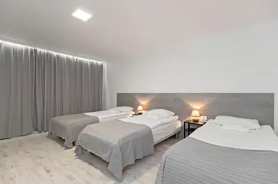 a hotel room with three beds and two tables at HappyInn Rooms in Kaunas