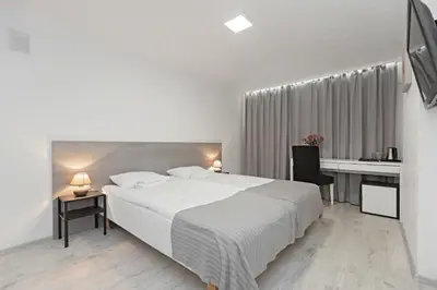 a white bedroom with a large bed and a desk at HappyInn Rooms in Kaunas