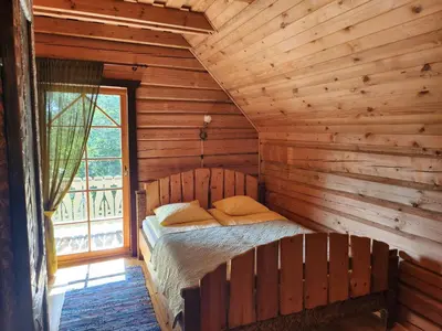 a bed in a log cabin with a window at Sodyba 