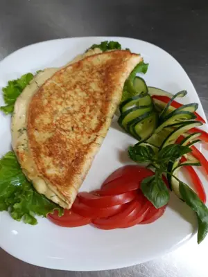 a white plate with a sandwich and vegetables on it at Sodyba 