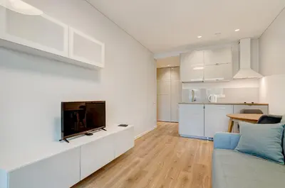 a white living room with a tv and a couch at City Studio 1B in a great location in Vilnius