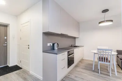 a kitchen with white cabinets and a table at Apartments Vilnius 1 near center with a roof terrace and parking in Vilnius