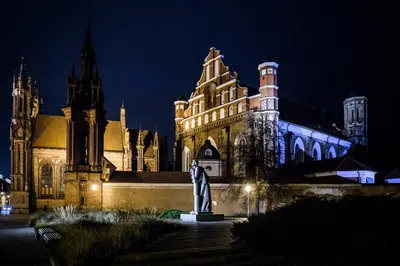 a building with a statue in front of it at night at Eliksyras Apartment in Vilnius