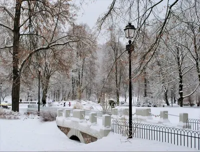 a park covered in snow with a street light and benches at Eliksyras Apartment in Vilnius