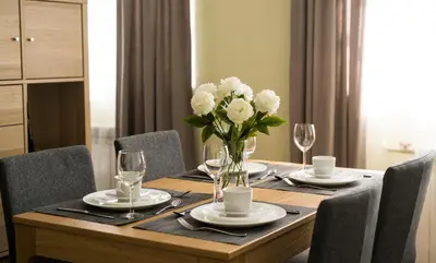 a wooden table with a vase of white flowers on it at Eliksyras Apartment in Vilnius
