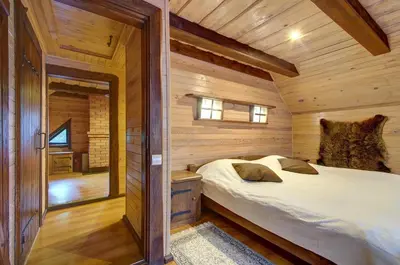 a bedroom with a bed in a wooden cabin at Prie Klykio in Utena