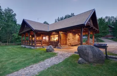 a large log cabin with a porch and some rocks at Prie Klykio in Utena