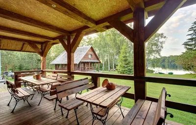 a porch with wooden tables and chairs and a large window at Prie Klykio in Utena