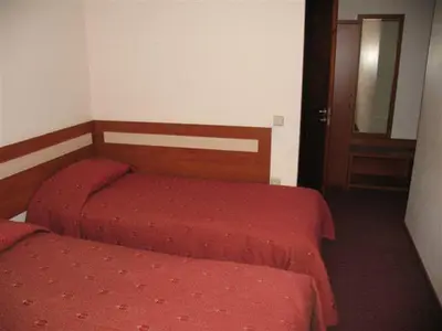 a bedroom with two beds with red sheets and a door at Hotel Ode Self Check-In in Alytus