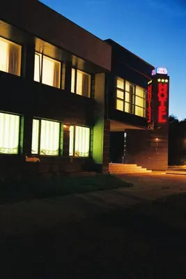 a building with a neon sign in front of it at Hotel Ode Self Check-In in Alytus