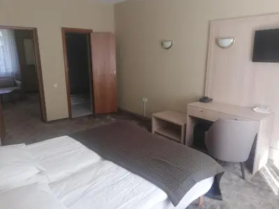 a bedroom with a white bed and a desk and a desk at Hotel Senas Namas in Alytus