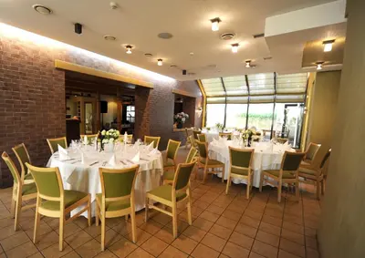 a dining room with white tables and chairs at Hotel Senas Namas in Alytus
