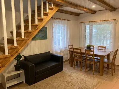 a living room with a dining room table and stairs at Holiday Homes Eliza in Druskininkai