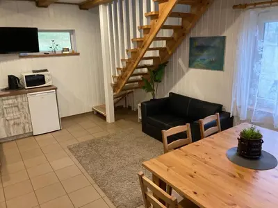 a living room with a table and a couch and a staircase at Holiday Homes Eliza in Druskininkai