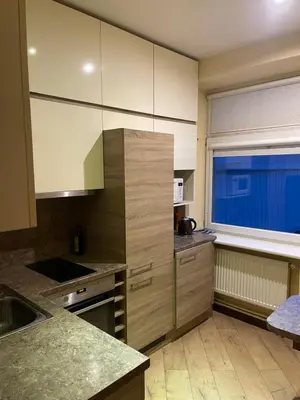 a kitchen with wooden cabinets and a window in it at Gintautas apartment in Šiauliai
