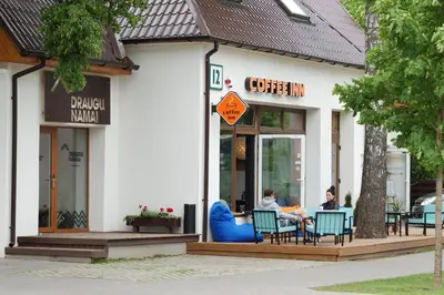 two people sitting at a table outside of a building at Draugų namai in Druskininkai