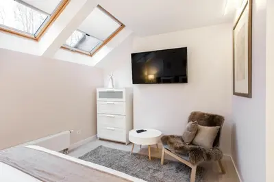 a room with a chair and a tv on a wall at Luxury for everyone - Hills Park Lux Apartments 3 in Vilnius