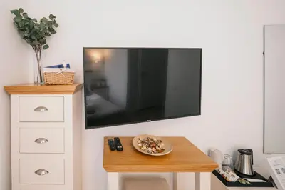 a flat screen tv hanging on a wall with a table at J14A I Rooms & Apartments AUTOMATED SELF CHECK-IN in Vilnius
