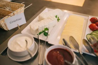 a plate of food with cheese and soup on a table at Sanatorija ,,Tulpės