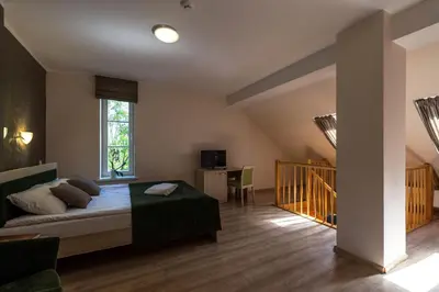 a bedroom with a bed and a desk and a staircase at Sanatorija ,,Tulpės