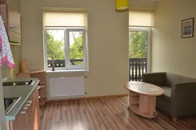 a kitchen with a couch and a table and two windows at Vila Evelina in Druskininkai