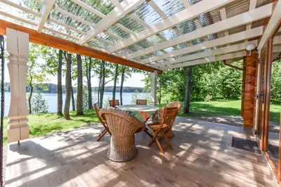 a patio with a table and chairs and a pergola at Mekų vila in Degučiai