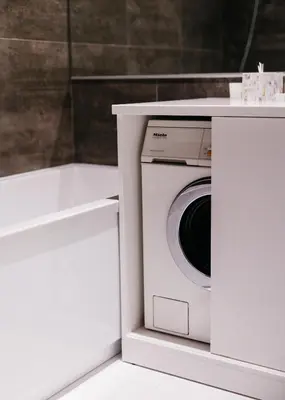 a washing machine in a white cabinet next to a bath tub at Islandijos gatvė in Vilnius