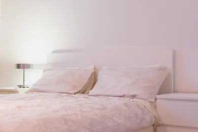 a white bedroom with a bed with white sheets and pillows at Islandijos gatvė in Vilnius