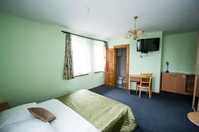 a bedroom with a bed and a desk and a television at Svečių namai Lingės in Nemėžis
