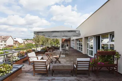 a deck with chairs and an umbrella on a building at Mineraliniai Apartamentai in Druskininkai