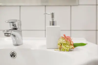 a flower sitting on a bathroom sink next to a faucet at Vila''RADIUM'' in Druskininkai