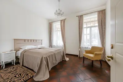 a bedroom with a bed and a chair and windows at Vila''RADIUM'' in Druskininkai