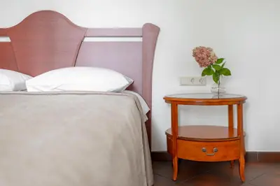 a bedroom with a bed and a nightstand with a vase of flowers at BURMISTRO NAMAS in Druskininkai
