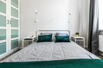a white bedroom with a large bed with green pillows at City Center apartment by URBAN RENT in Vilnius