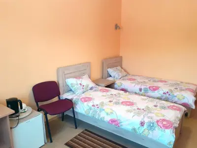 a bedroom with two beds and a red chair at Kambarių nuoma - Neveronys SAURIDA in Neveronys