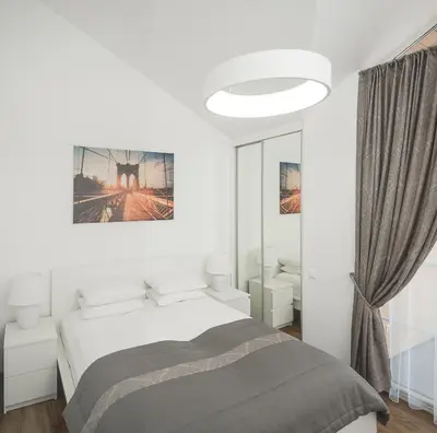 a white bedroom with a bed and a mirror at Laurentroom Park&Fountain in Ukmergė