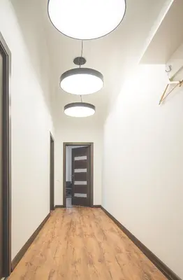 an empty room with white walls and a wooden floor and lights at Laurentroom Park&Fountain in Ukmergė