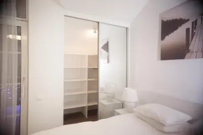 a white bedroom with a bed and a mirror at Laurentroom Park&Fountain in Ukmergė