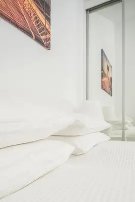 a bedroom with white sheets on a bed at Laurentroom Park&Fountain in Ukmergė