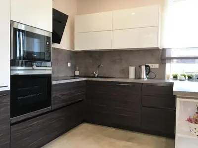 a kitchen with white cabinets and black appliances at Radvi House in Druskininkai
