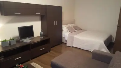 a bedroom with a bed and a television and a chair at Apartamentai Dainų II in Šiauliai