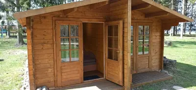 a wooden dog house with a door and windows at Biržai camping in Biržai