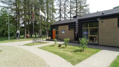 a small building with trees in a park at Biržai camping in Biržai