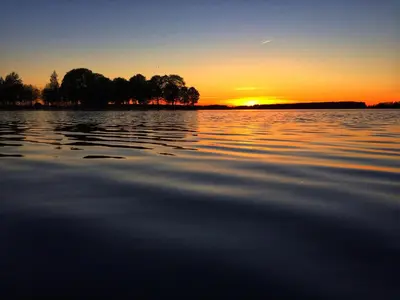 a sunset over a large body of water at Biržai camping in Biržai