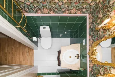 a bathroom with a toilet and a green tiled wall at Inner Blossom in Kaunas