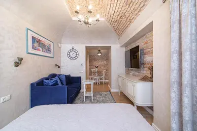 a bedroom with a bed and a blue couch and a kitchen at Luxury apartment in Pilies street in Vilnius