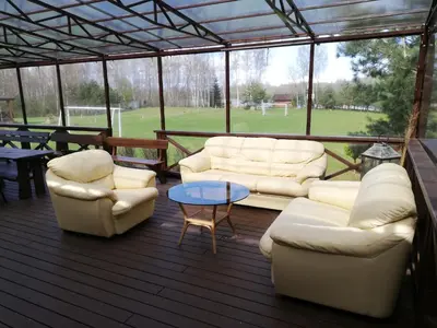 a screened in porch with couches and a table at Aido ir Vido sodyba in Utena