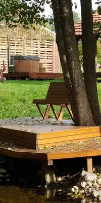 a wooden picnic table sitting next to a tree at Antanelio Sapnas in Pabradė